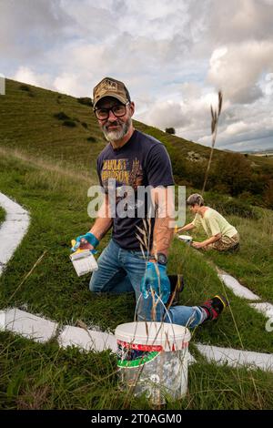 Volunters malen die Betonsteine, aus denen der lange Mann von Wilmington in East Sussex besteht. Ursprünglich wurde er in die Kreide des South Down gehauen. Stockfoto