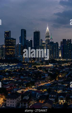 Blick auf Kampung Datuk Keramat bei Nacht mit der Skyline des Stadtzentrums von Kuala Lumpur und den Petronas-Türmen im Hintergrund Stockfoto