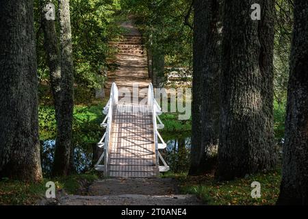 Aspen Gasse mit einem Sandweg und einer weißen Brücke über den Teich im Herrenpark. Stockfoto