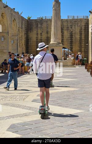 Valletta, Malta - 3. August 2023: Besucher der Stadt mit einem gemieteten Elektroroller in den Gärten der Befestigungsanlagen von Valletta. Stockfoto