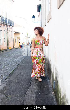 Porträt einer schönen rothaarigen Frau in farbenfrohem langen Kleid, die auf der Straße der Stadt spaziert. Glücklicher Reisender. Stockfoto