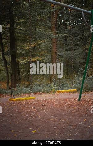 Leere Schaukel auf dem Spielplatz. Ein alter verlassener Spielplatz im Wald. Gruseliger ruhiger Ort. Horrorschaukeln ohne Kinder. Herbstdepressionskonzept. Stockfoto