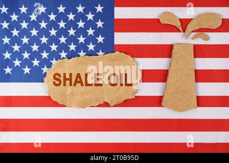 Auf der US-Flagge befindet sich eine aus Pappe geschnittene Ölplattform und ein Schild mit der Aufschrift Schiefer Oil. Stockfoto