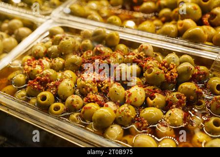 Gewürzte Oliven in einem Behälter mit Marinat auf der Theke. Straßenmarkt. Stockfoto