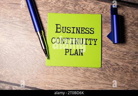 Schwarzer Pancel schreibt einen Text für DEN BUSINESS CONTINUITY PLAN auf dem gelben HINTERGRUND Stockfoto