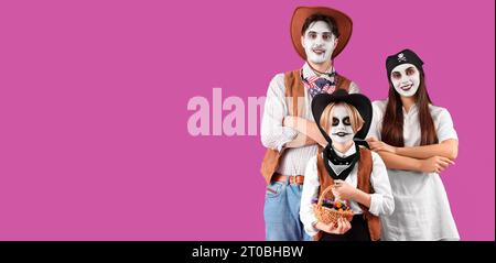 Glückliche Familie, die zu Halloween auf magentafarbenem Hintergrund gekleidet ist, mit Platz für Text Stockfoto