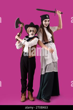 Kleiner Junge mit seiner Mutter, die zu Halloween auf lila Hintergrund gekleidet ist Stockfoto