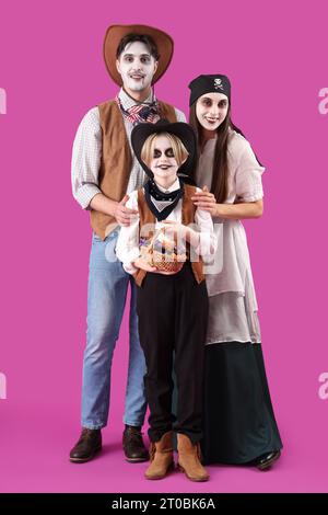 Glückliche Familie, die zu Halloween auf violettem Hintergrund gekleidet ist Stockfoto