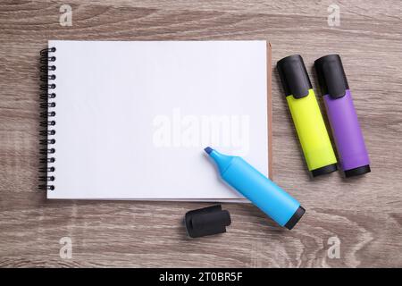 Leeres Notizbuch und Markierungen auf Holztisch, flach gelegt Stockfoto