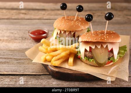 Niedliche Monster Burger serviert mit Pommes frites und Ketchup auf Holztisch, Platz für Text. Halloween Party Essen Stockfoto