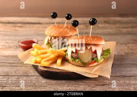 Süße Monster Burger serviert mit Pommes frites und Ketchup auf Holztisch. Halloween Party Essen Stockfoto