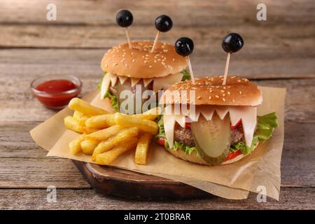 Süße Monster Burger serviert mit Pommes frites und Ketchup auf Holztisch. Halloween Party Essen Stockfoto