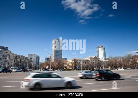 Bild von Autos, die am Platz Piata Victoriei in Bukarest, Rumänien, vorbeifahren. Der Siegesplatz ist einer der großen öffentlichen Plätze in Bukarest, Rumänien, an in Stockfoto