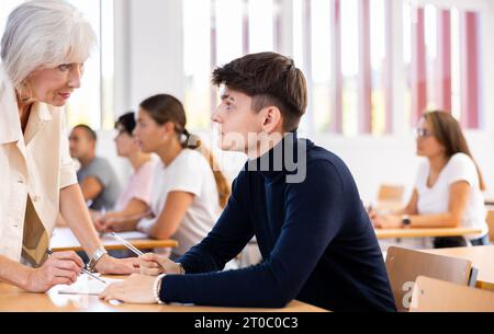 Alte Lehrerin, die dem Jungen hilft, Probleme im Unterricht zu lösen Stockfoto