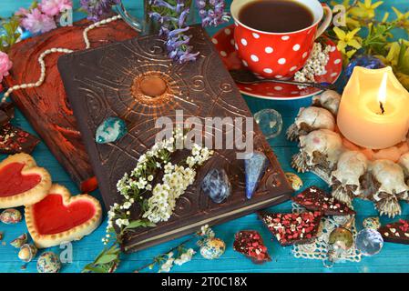 Kerze und Zauberbuch auf dem Hexenaltar-Tisch. Okkultes, esoterisches und Wahrsagungsstilleben. Mystischer Hintergrund mit Vintage-Objekten Stockfoto