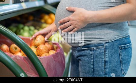 Schwangere Frau wählt Äpfel im Laden. Stockfoto