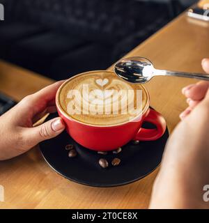 Frauenhände halten Latte Art Kaffeetasse Stockfoto