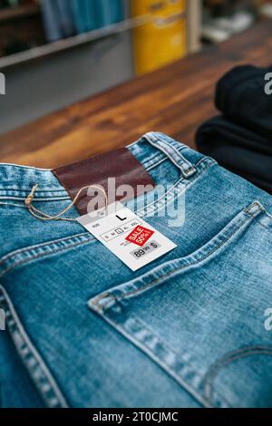 Detail des Labels mit Rabattpreis über einer blauen Jeanshose im Vintage-Shop Stockfoto