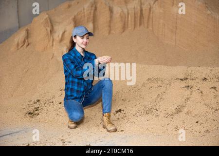 Bäuerin hockt auf einem Haufen Sojabohnenschalen Stockfoto