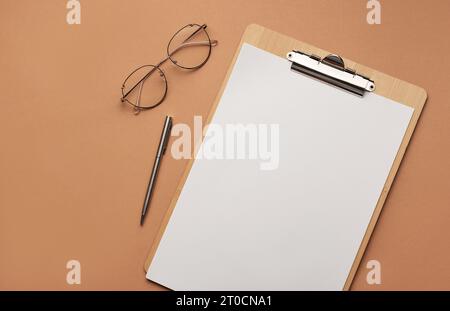 Klemmbrett mit leerem Blatt und Brille, Arbeitsplatz. Stockfoto