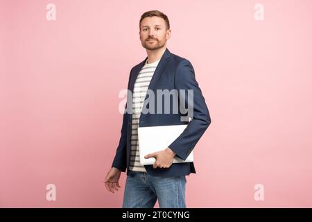 Man Trader, Krypto-Investor, Unternehmer, Finanzier mit Laptop in den Händen auf rosafarbenem Hintergrund. Stockfoto