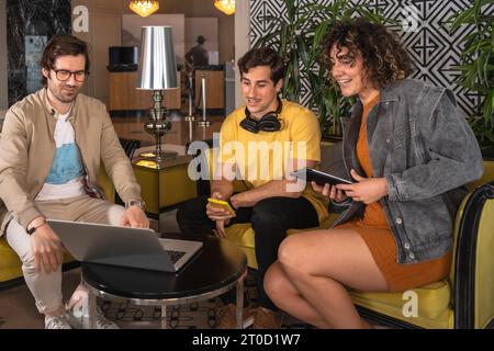 Begeisterte männliche und weibliche Profis tauschen sich während des Sitzens in der Hotellobby aus Stockfoto