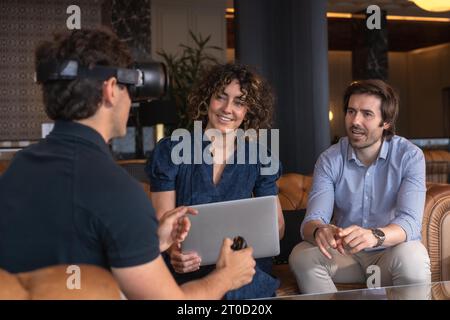 Zwanglose Geschäftsleute, die eine VR-Brille bei einem Meeting in einem Saal eines Hotels verwenden Stockfoto