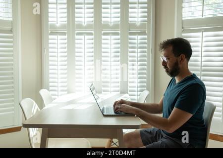 Ein bärtiger Mann in Brille arbeitet am Laptop Stockfoto