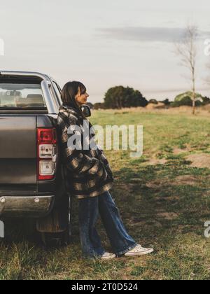 Eine Frau im mittleren Alter, die sich auf ihren Pickup lehnt. Vertikale Aufnahme Stockfoto