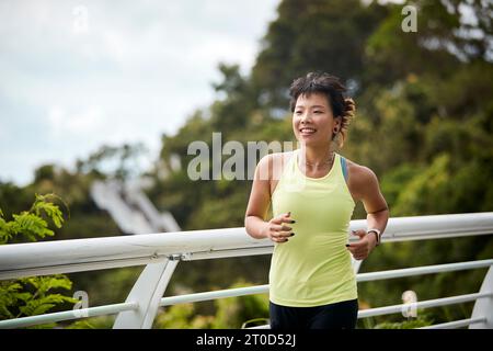 Junge asiatische Frau, die im Stadtpark Joggen läuft Stockfoto