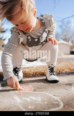 Kleinkind zeichnet mit Kreide an windigen Tagen. Stockfoto