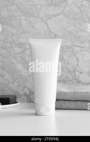 Weiße Tube Creme Mockup mit Seife und Handtuch auf dem weißen Tisch. Stockfoto