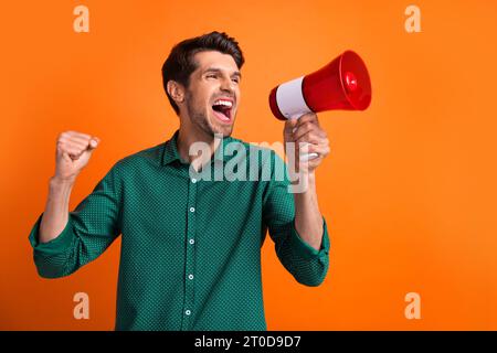 Foto von Aktivist Faust hoch schreiend Megaphon Mann Workaholic braucht seinen Gehaltsboss ignorieren seine Beförderung isoliert auf orangefarbenem Hintergrund Stockfoto