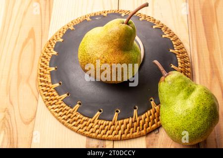 Zwei süße Birnen mit Keramikplatte, Nahaufnahme, auf einem Holztisch. Stockfoto