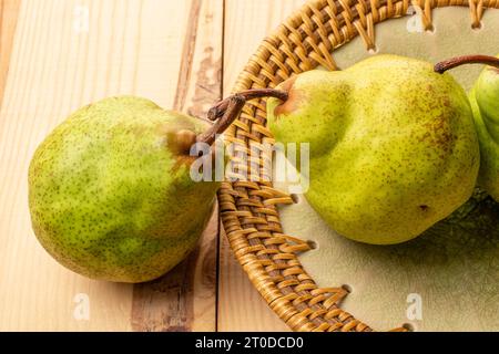 Zwei süße Birnen mit Keramikplatte, Nahaufnahme, auf einem Holztisch. Stockfoto