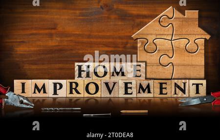 Puzzleteile aus Holz, die eine Hausform bilden, auf einer Holzwerkbank mit Text Hausverbesserung aus Holzblöcken. Hausverbesserungskonzept. Stockfoto
