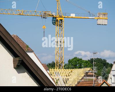 Durch ein Teleobjektiv erfasst, entfaltet sich ein Panorama von Dächern, unterbrochen von einem hochaufragenden Kran, der aktiv am Bau eines Gebäudes beteiligt ist. Stockfoto