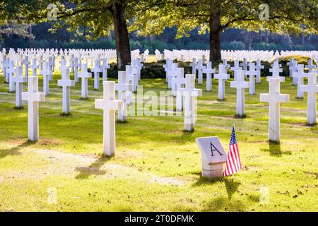 Weiße Marmorkreuze auf dem Normandie American Cemetery and Memorial in Colleville, einem Militärfriedhof aus dem Zweiten Weltkrieg in der Nähe von Omaha Beach, mit amerikanischer Flagge. Stockfoto