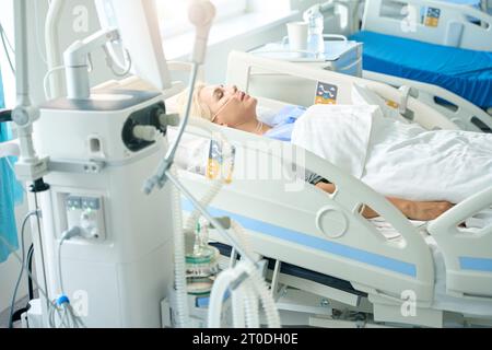 Lady liegt auf einem speziellen Bett, sie ist mit medizinischen Geräten verbunden Stockfoto