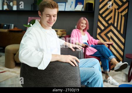 Ein lächelnder Mann und eine lächelnde Frau sitzen in bequemen Sesseln Stockfoto