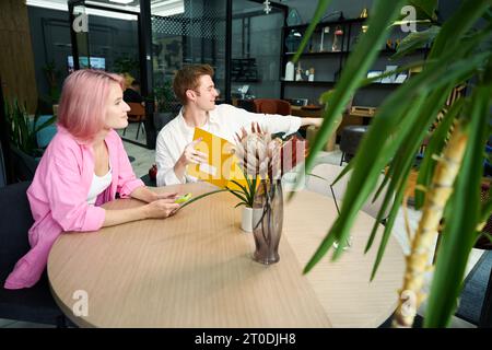 Ein Typ mit Freundin sitzt am Tisch im Möbelausstellraum Stockfoto