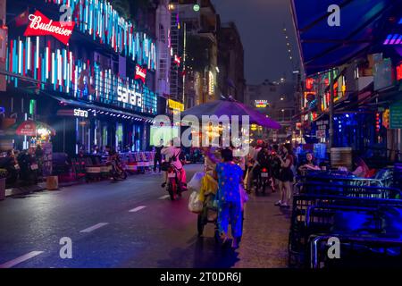 Vietnamesische Street Food-Verkäuferin schiebt ihren Wagen die Bui Vien Walking Street in Night, Ho Chi Minh City, Vietnam Stockfoto