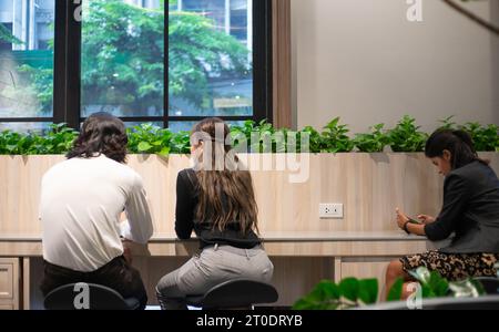 Junge asiatische Geschäftsfrau, die mit ihrem Kollegen spricht. Eine indische Geschäftsfrau, die das Handy benutzt. Stockfoto