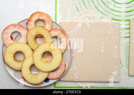 Reife Apfelringe und ein Quadrat Blätterteig zum Backen. Draufsicht. Stockfoto