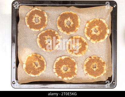 Backblech mit Apfelringen im Teig auf Backpapier. Hausmannskost. Stockfoto