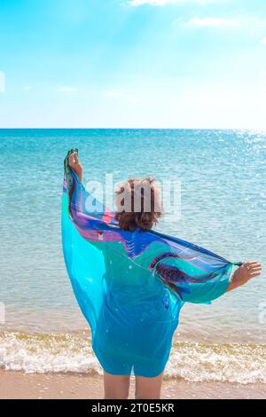 Eine Dame in Badeanzug und blauem Pareo ruht an einem Sommertag am Meer. Stockfoto