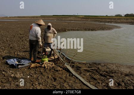 Wonogiri, Zentral-Java, Indonesien. Oktober 2023. Zwei Bauern überprüfen einen Schlauch für die Bewässerung von Reisfeldern im Trocknungs-Gajah-Mungkur-Reservoir im Bezirk Wuryantoro. Die Trockenzeit dieses Jahres wird voraussichtlich länger anhalten, nämlich bis Ende 2023 bis Anfang 2024, was die Auswirkungen von El Nino sind. Derzeit ist die Rohwassermenge aus dem Gajah Mungkur Reservoir im Oberlauf des Bengawan Solo River in der Wonogiri Regency, Zentraljava, drastisch zurückgegangen. (Kreditbild: © Angga Budhiyanto/ZUMA Press Wire) NUR REDAKTIONELLE VERWENDUNG! Nicht für Commerci Stockfoto