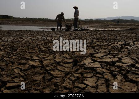 Wonogiri, Zentral-Java, Indonesien. Oktober 2023. Zwei Bauern überprüfen einen Schlauch für die Bewässerung von Reisfeldern im Trocknungs-Gajah-Mungkur-Reservoir im Bezirk Wuryantoro. Die Trockenzeit dieses Jahres wird voraussichtlich länger anhalten, nämlich bis Ende 2023 bis Anfang 2024, was die Auswirkungen von El Nino sind. Derzeit ist die Rohwassermenge aus dem Gajah Mungkur Reservoir im Oberlauf des Bengawan Solo River in der Wonogiri Regency, Zentraljava, drastisch zurückgegangen. (Kreditbild: © Angga Budhiyanto/ZUMA Press Wire) NUR REDAKTIONELLE VERWENDUNG! Nicht für Commerci Stockfoto