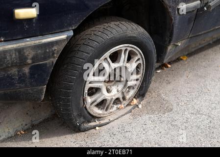 Close-up beschädigten Reifens. Das Rad der PKW-Reifen lecken. Reifenpanne warten auf die Reparatur. Verlassenes Auto auf dem Parkplatz. Stockfoto
