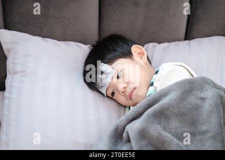 Sie war krank und hatte einen fiebersenkenden Fleck auf der Stirn. Sie lag auf dem Bett. Stockfoto